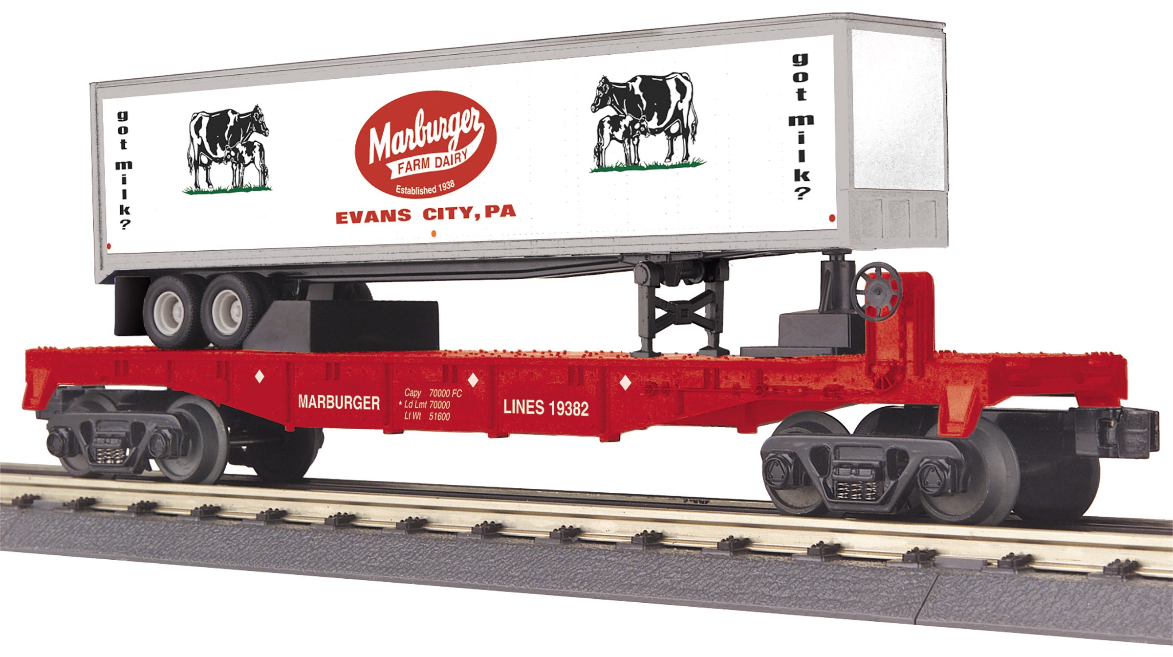 Red flat car sitting on train track with a white "Marburger" trailer load