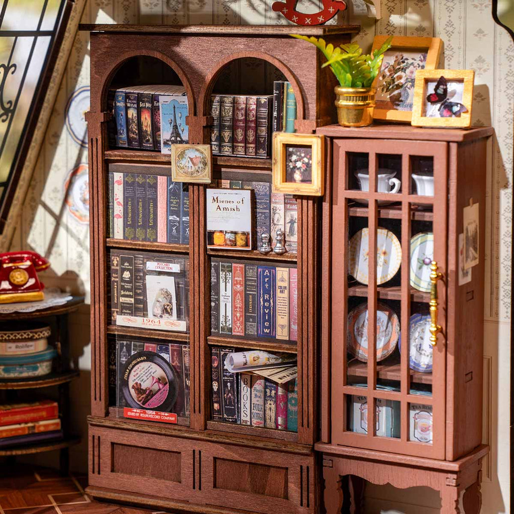 Wooden bookshelf with books, decorative items, and a small plant in Catherine's living room miniature kit.