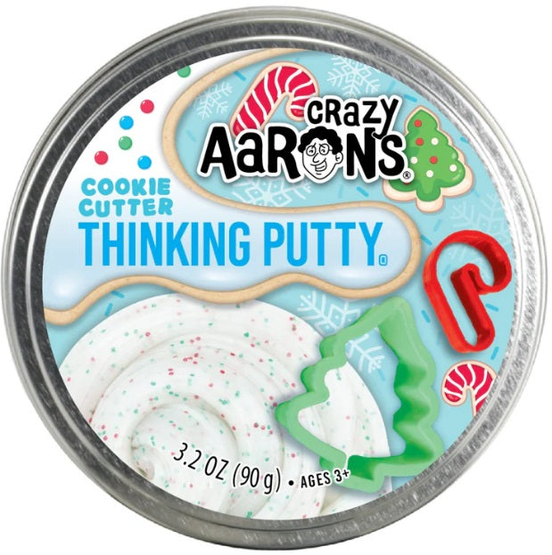 Round metal tin of white putty with red and green dots in it and candy cane and Christmas tree shaped cookies cutters.