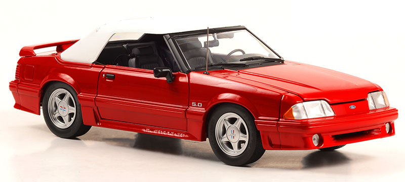 A 1/18 scale diecast model of a red 1991 Mustang GT Convertible with a white top, black interior, and silver wheels.