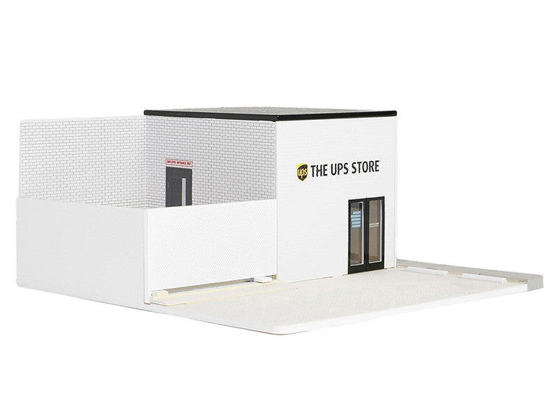 Diorama of a White building with the UPS logo and the words "THE UPS STORE" above the door, with 2 parking space in front of the building and a fenced in section next to the building.