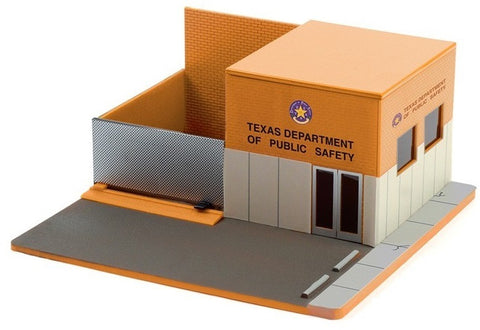 Diorama of a public safety building with parking lot in front to display model cars.