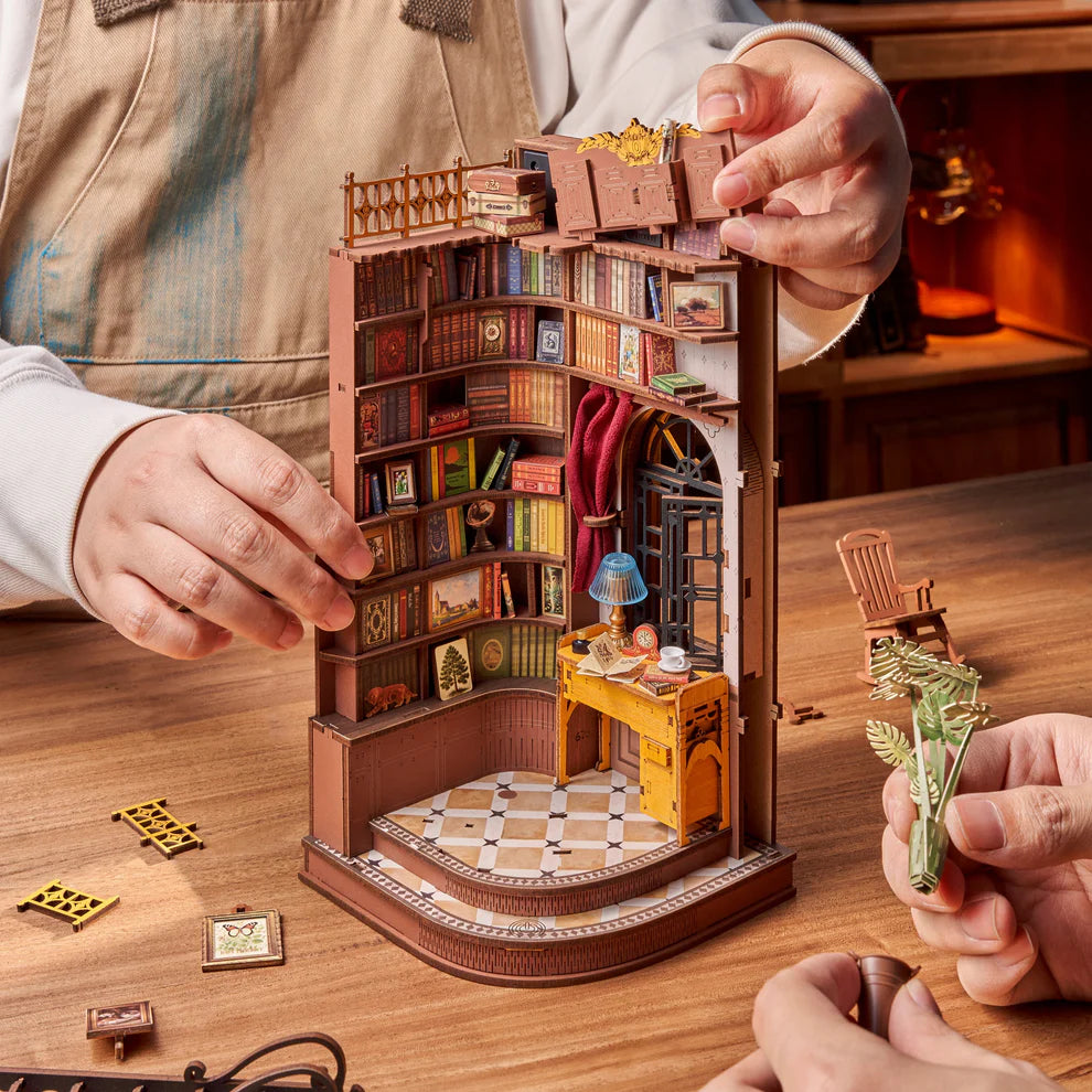 Hands assembling miniature book nook kit.