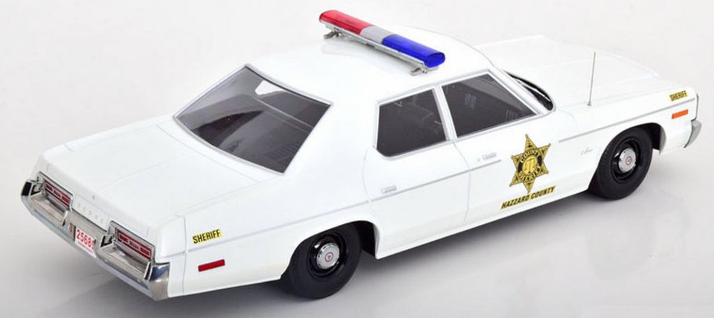 A 1/18 scale model of a 1974 Dodge Monaco Hazzard County Police Sheriff car in white color with red and blue light bar on roof.