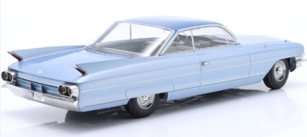 A 1/18 scale model of a 1961 Cadillac Series 62 Coupe DeVille in light blue metallic color.