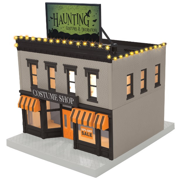 O scale 2 story building with billboard on top that reads "Haunting Costumes & Deocrations"