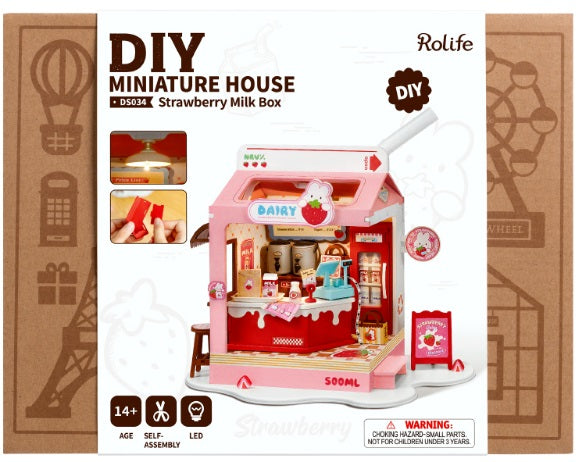 A pink strawberry-themed miniature milk box shop with accessories, packaged in a box showing the assembled product.