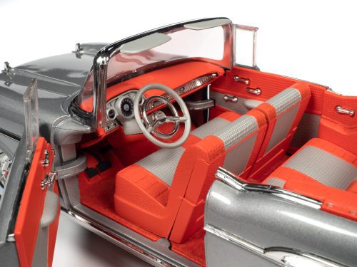A 1/18 scale model of a 1957 Chevrolet Bel Air Convertible in silver color and red interior