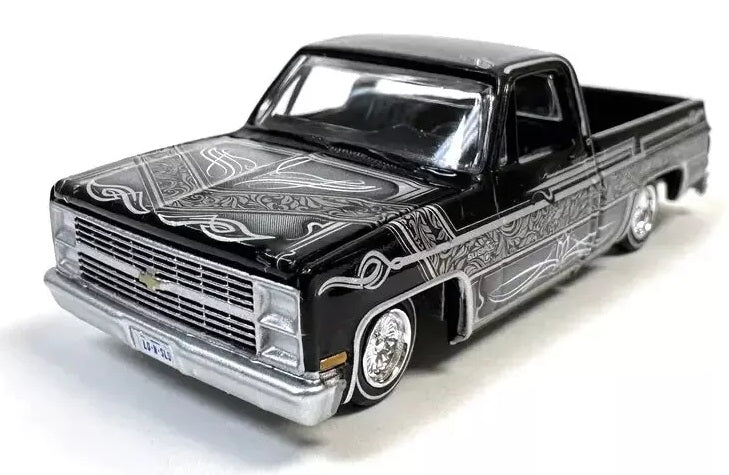 1/64 Scale model of a black Chevy Silverado with silver pin striping and low rider chassis.