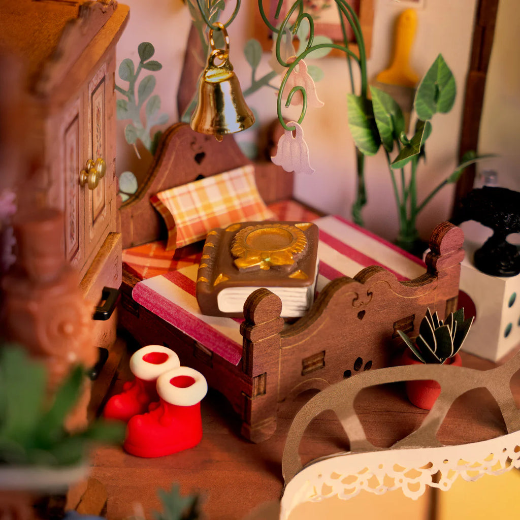 Close-up of a miniature wooden desk with books, plants, and decorative items in a cozy room setting.
