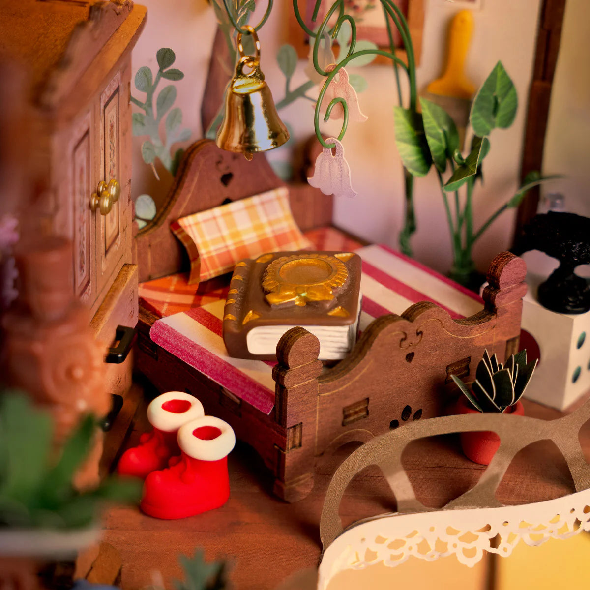 Close-up of a miniature wooden desk with books, plants, and decorative items in a cozy room setting.