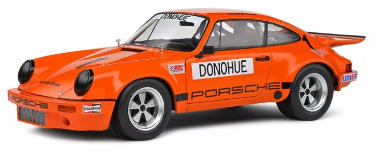 1/18 scale model of a Porsche 911 IROC in orange with the number 1 and 'DONOHUE' branding.