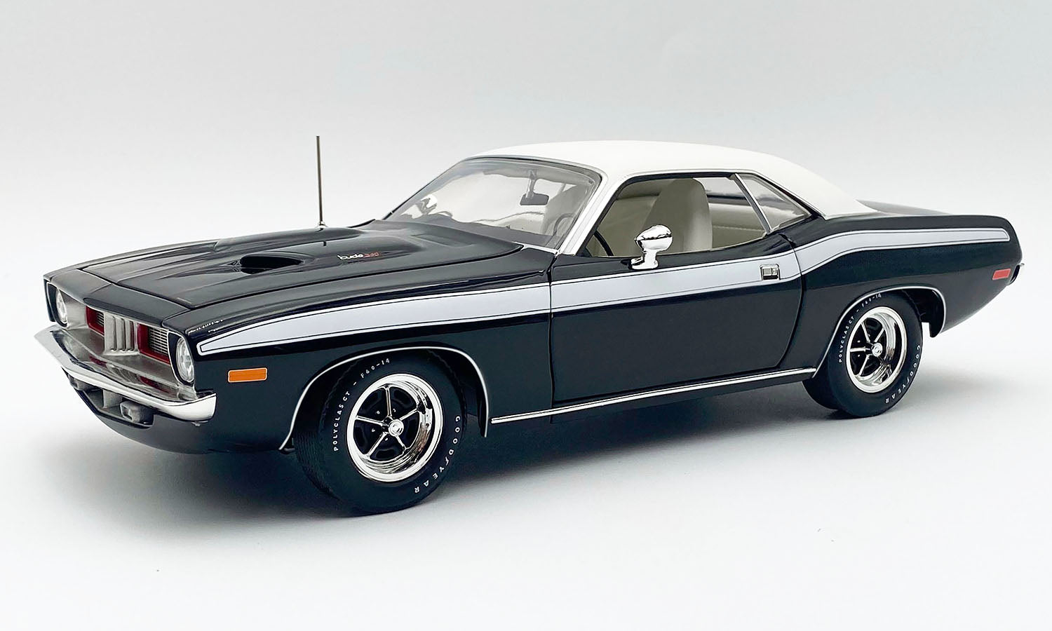 A 1/18 Scale model car of 1972 Plymouth Cuda in black with a white stripe and white roof.