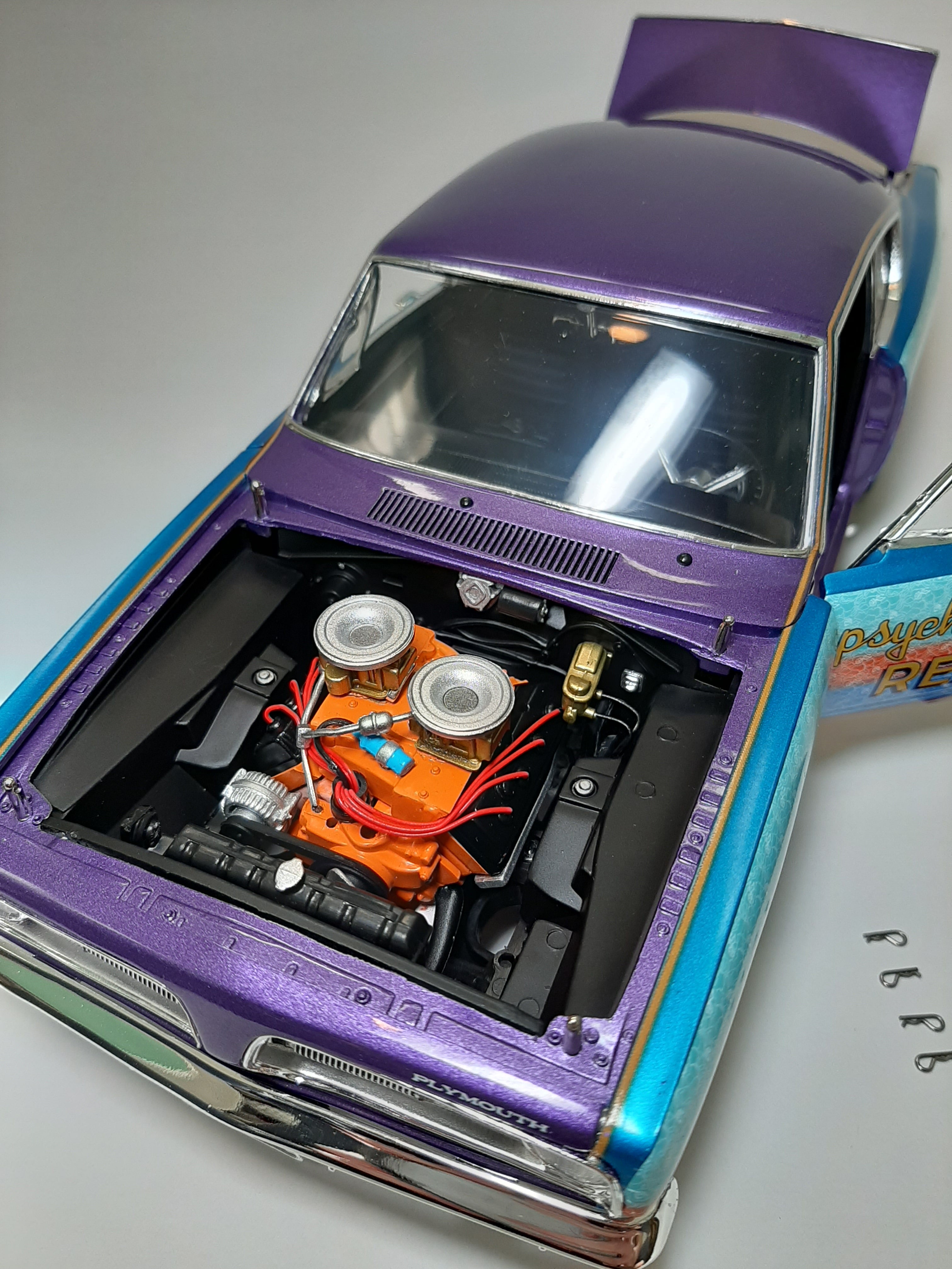A 1/18 scale diecast model of a 1968 Plymouth Barracuda with a colorful "Psychotic Reaction" decal on the side.
