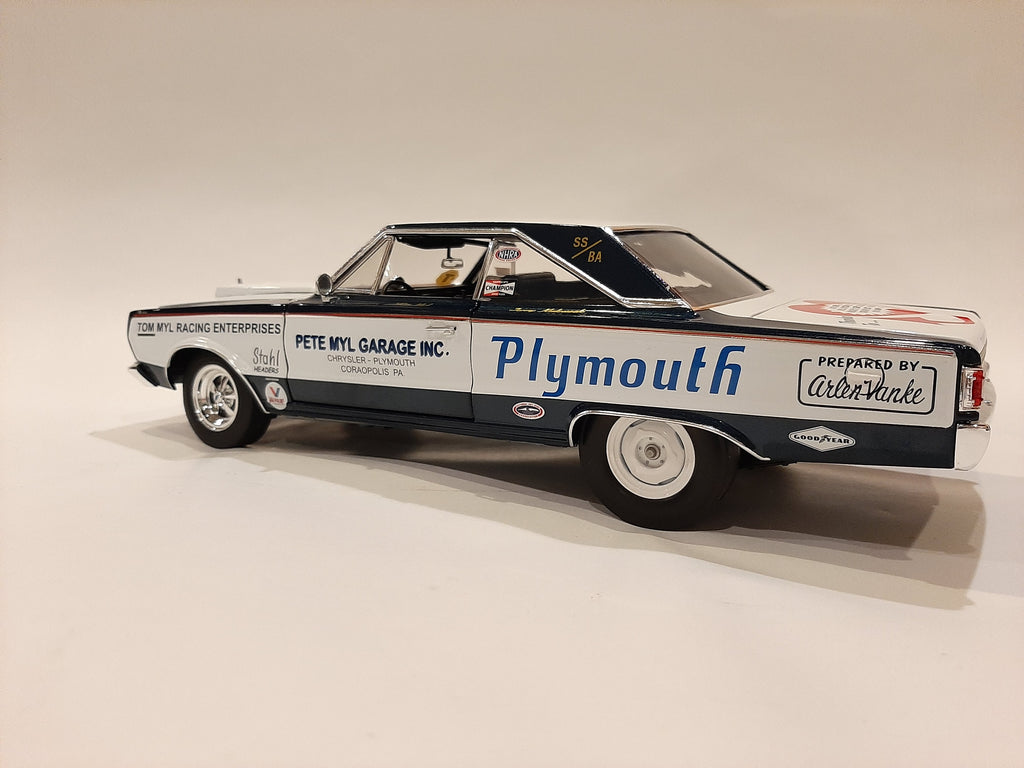 A 1/18 scale model of a 1967 Plymouth Belvedere in white with blue and black detailing, resembling a racing car with sponsor decals.
