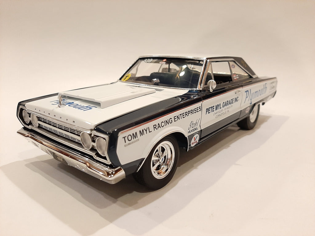 A 1/18 scale model of a 1967 Plymouth Belvedere in white with blue and black detailing, resembling a racing car with sponsor decals.