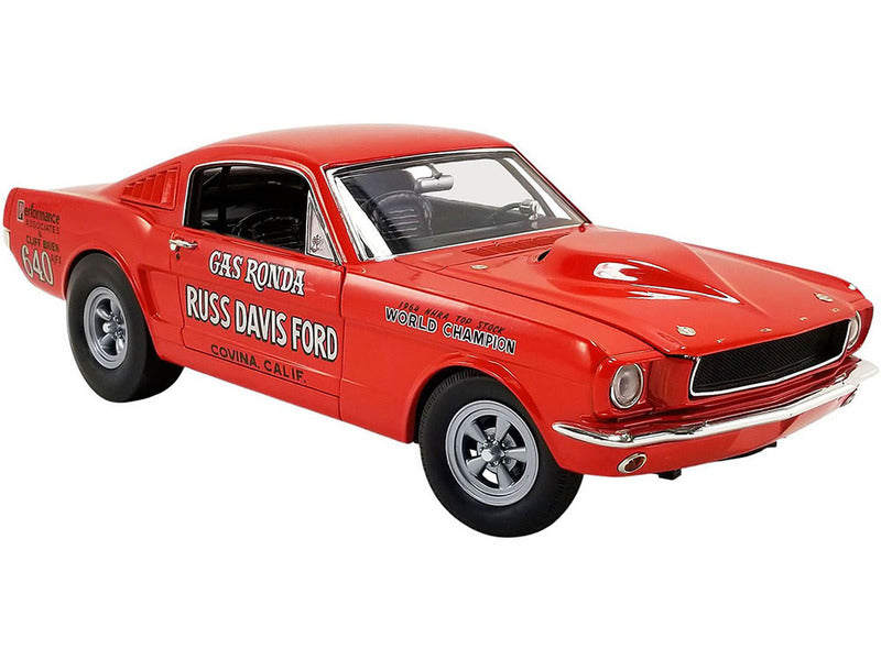 1/18 scale model of a 1965 Ford Mustang GT in red with "Gas Ronda" and other words painted on the sides.