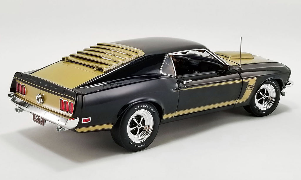 A 1/18 scale diecast model car of a black and gold 1969 Ford Mustang Boss 429.