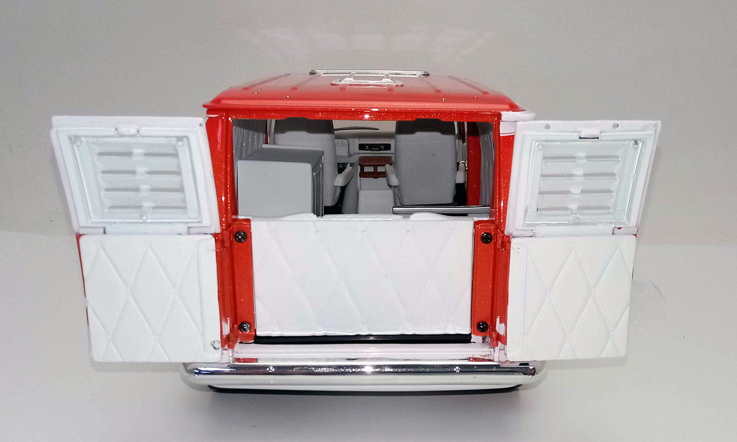 Open back doors on a 1/18 scale model of a red 1976 Chevy G-Series Van.
