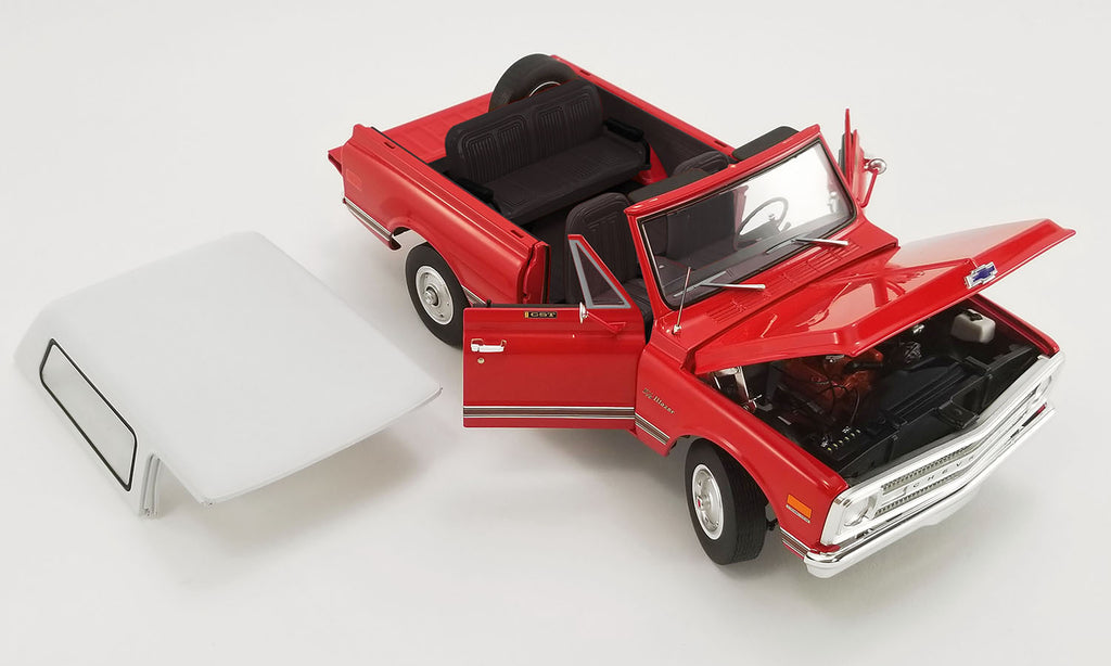 1/18 scale model of a red 1969 Chevrolet Blazer K/5 with white roof sitting next to the car and doors open.