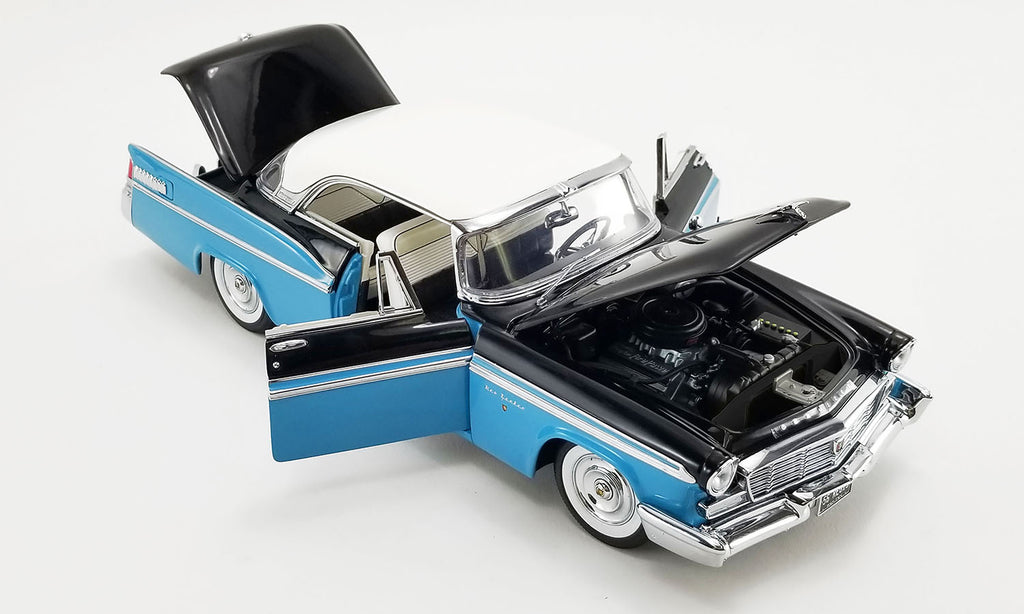 A 1/18 scale model of a 1956 Chrysler New Yorker St. Regis in Stardust Blue and black with a white roof showing open doors, hood, and trunk.