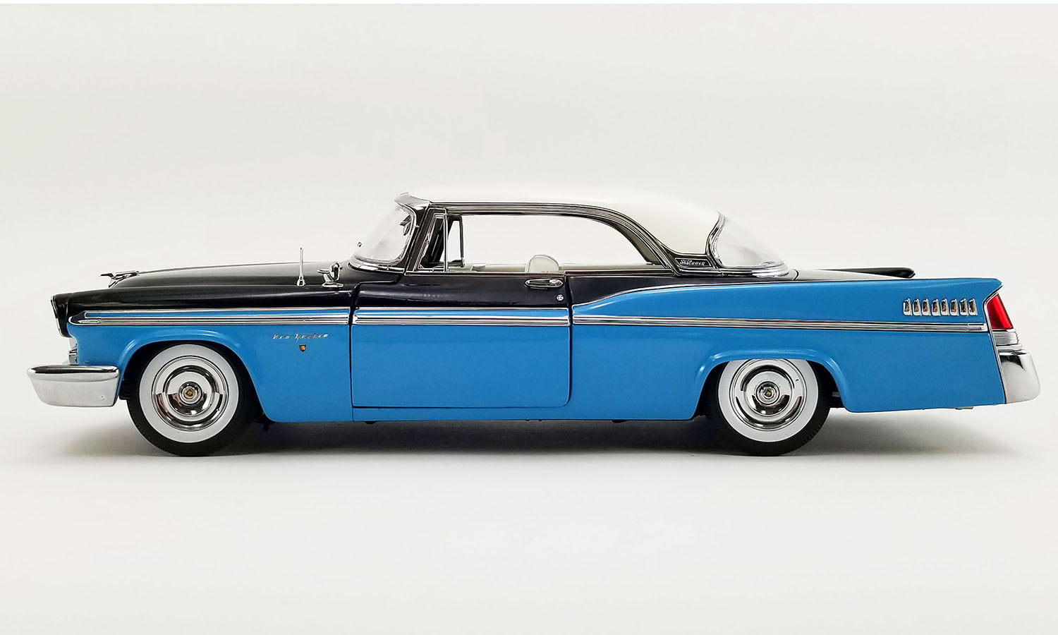 A 1/18 scale model of a 1956 Chrysler New Yorker St. Regis in Stardust Blue and black with a white roof.
