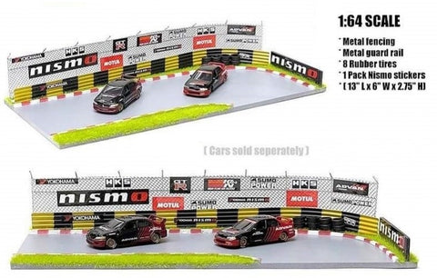 1/64 scale model of a racetrack diorama with metal fencing, metal guard rail, and two toy cars. Includes a pack of NISMO branded stickers.