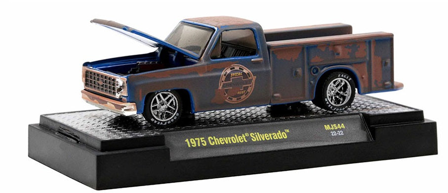 Scale model of a 1975 Chevrolet Silverado work truck in blue and rust on a display base.