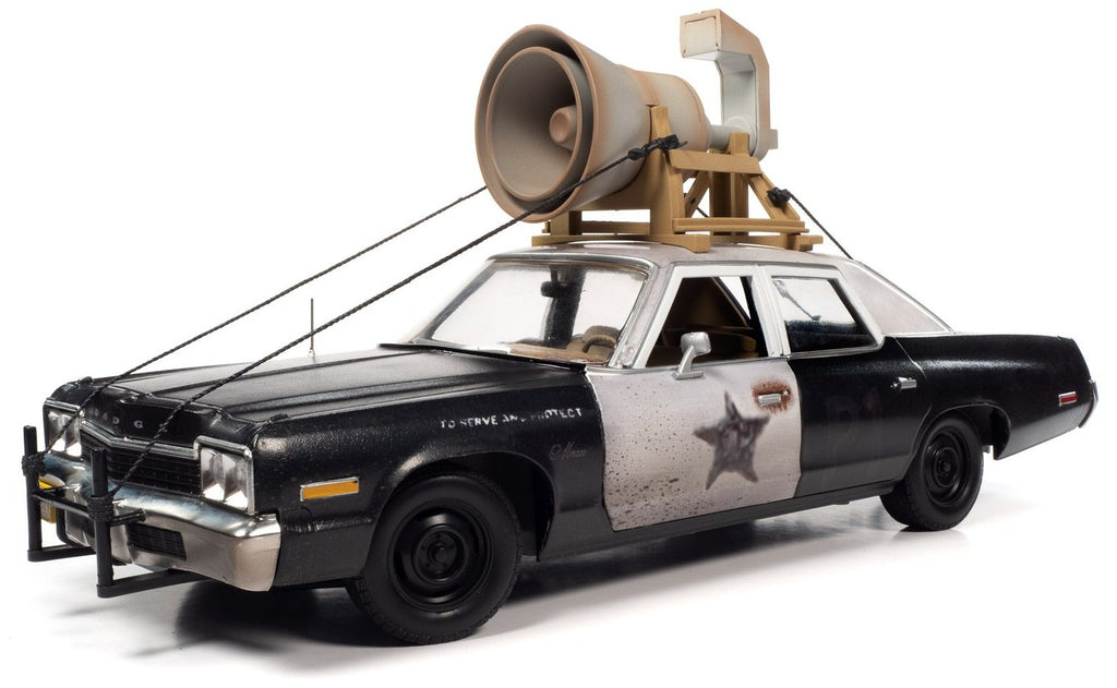 1/18 scale model of a 1974 Dodge Monaco Police Pursuit car from the Blues Brothers movie, with a black and white color scheme with a large speaker attached to the top. 