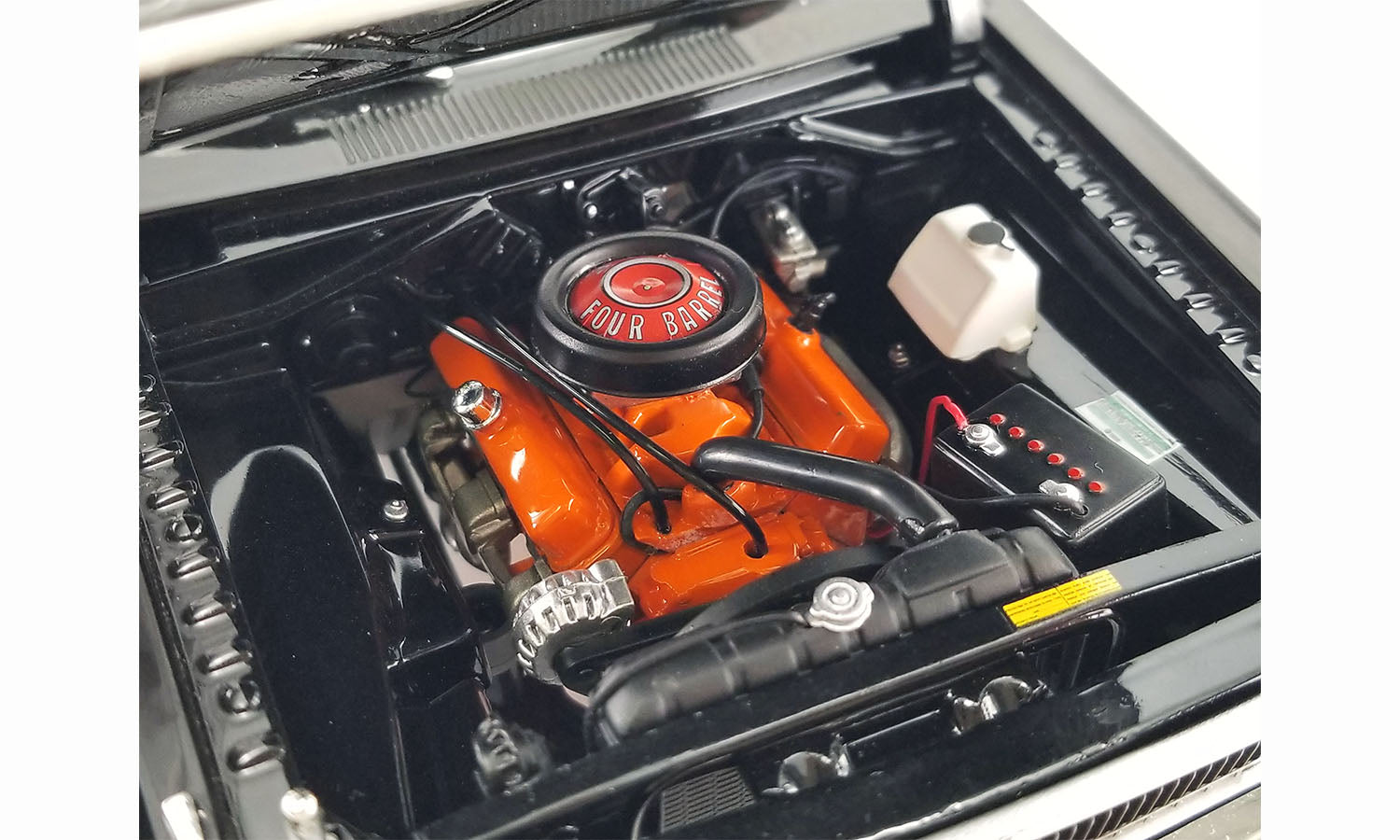 View of engine under the opening hood 1/18 scale diecast car of a 1970 Dodge Dart Swinger 340 with a white tail stripe
